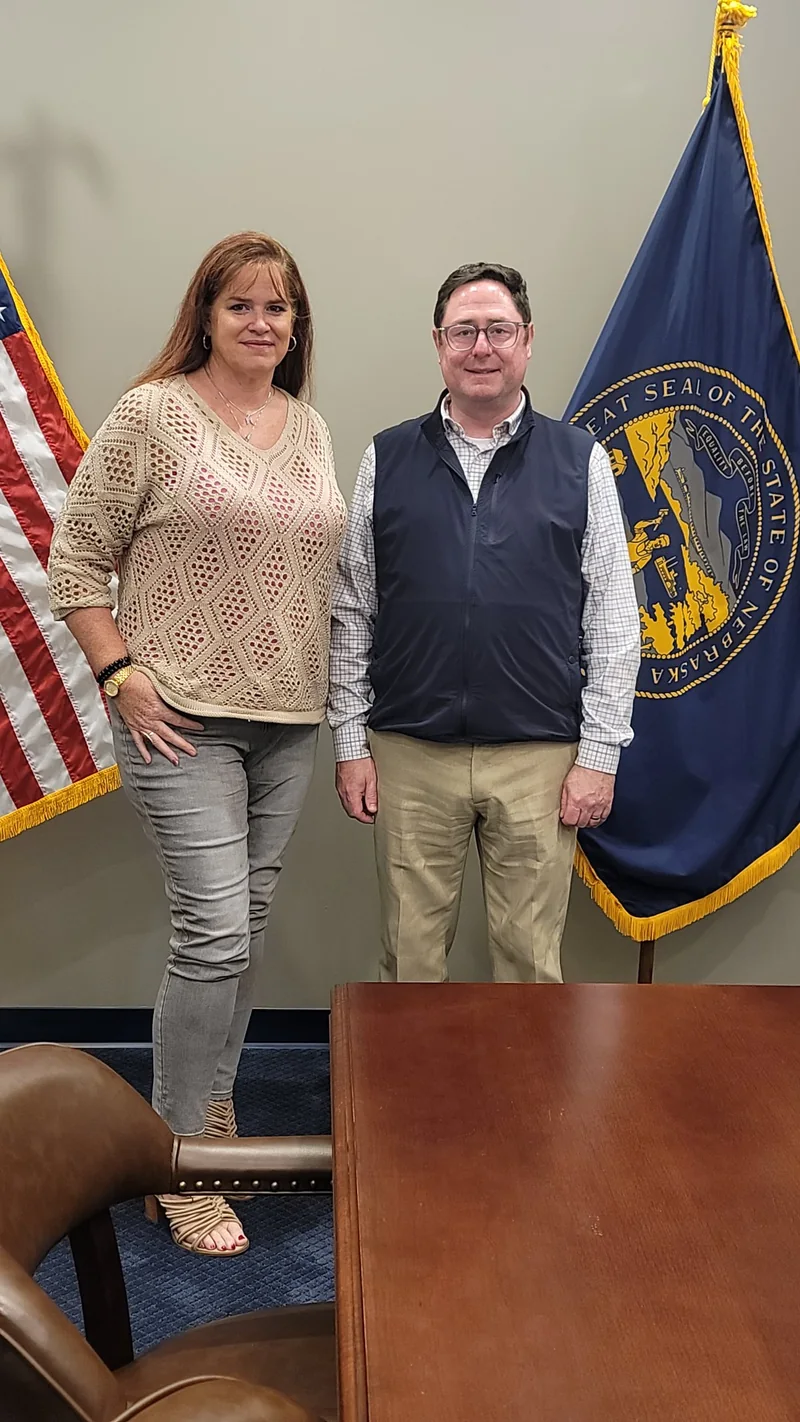 VINA founder Amber Wood with U.S. Representative Mike Flood beside the American and Nebraska flags.