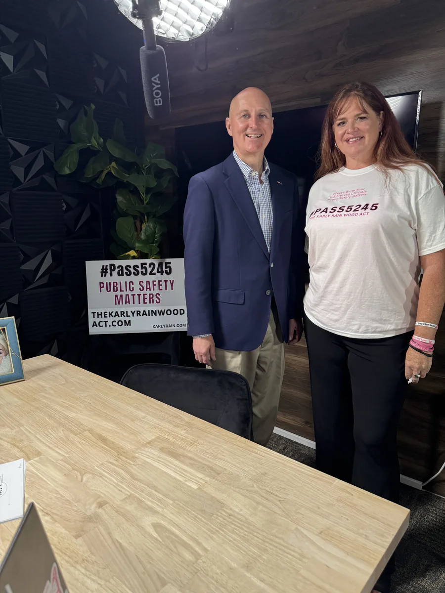 VINA founder Amber Wood with U.S. Senator Pete Ricketts in a podcast studio, beside a #Pass5245 Public Safety Matters sign.